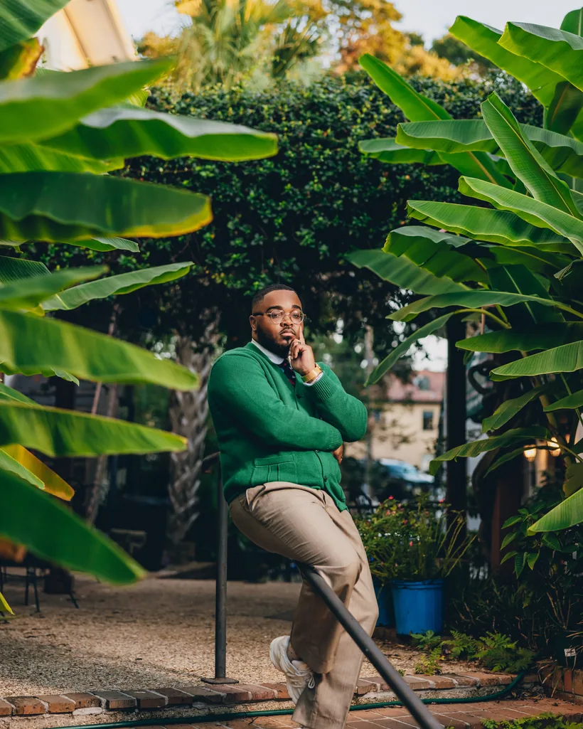 Eugene B. Lee-Johnson in a green cardigan among tropical foliage